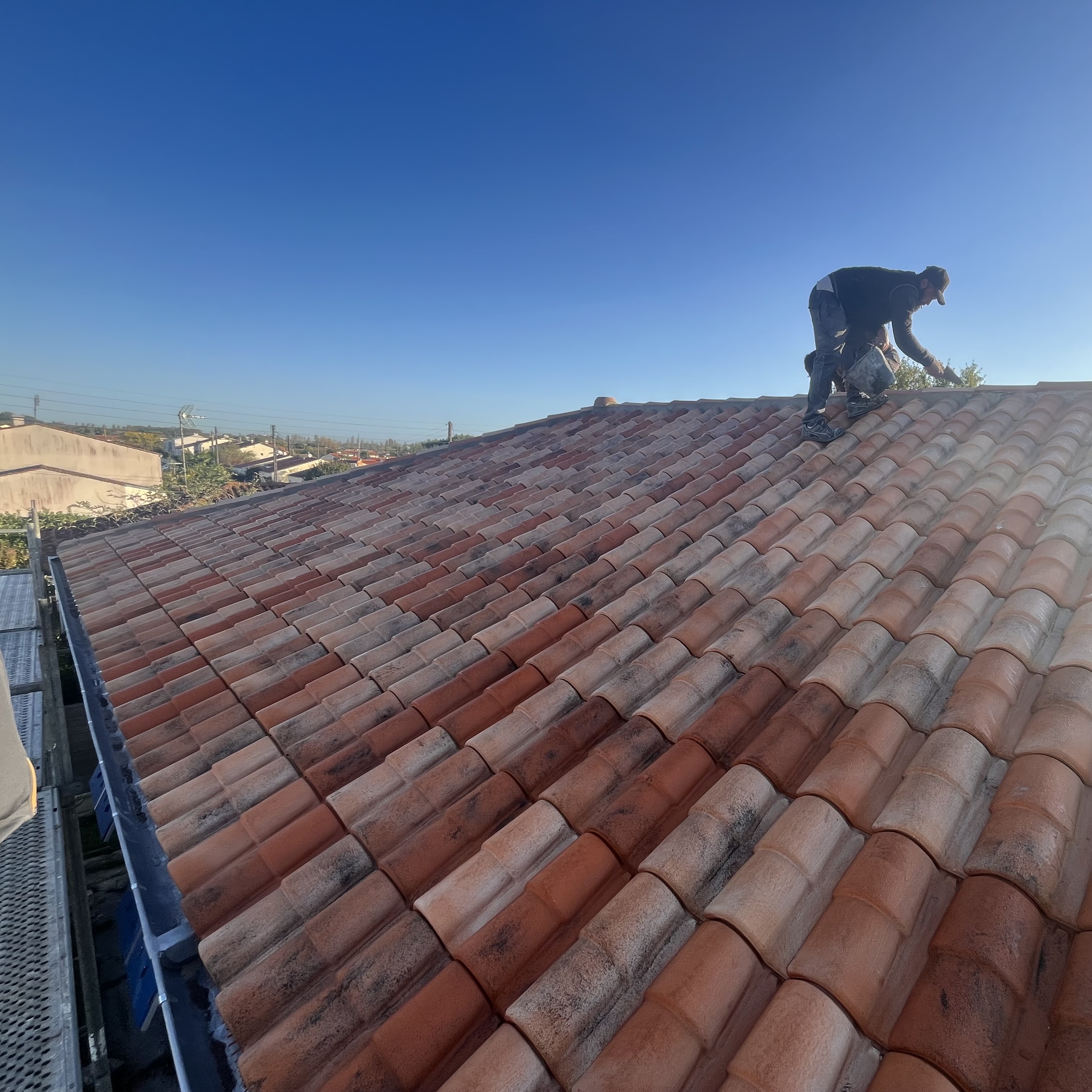 couverture en cours de finition, un ouvrier est sur le toit en train de finaliser le faîtage